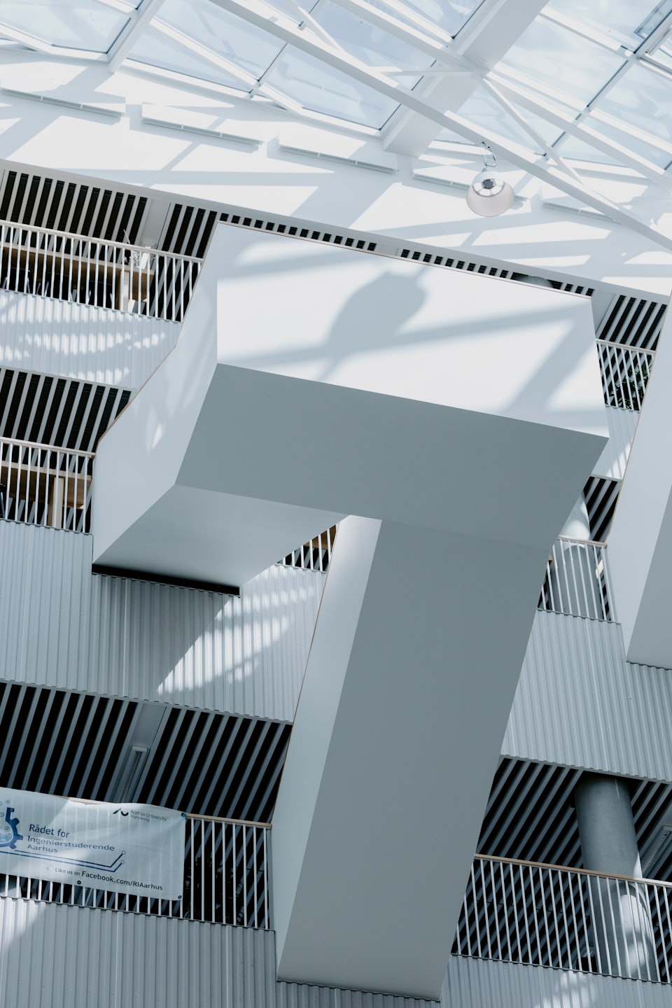 Modern white building interior with geometric shadows and a glass ceiling.