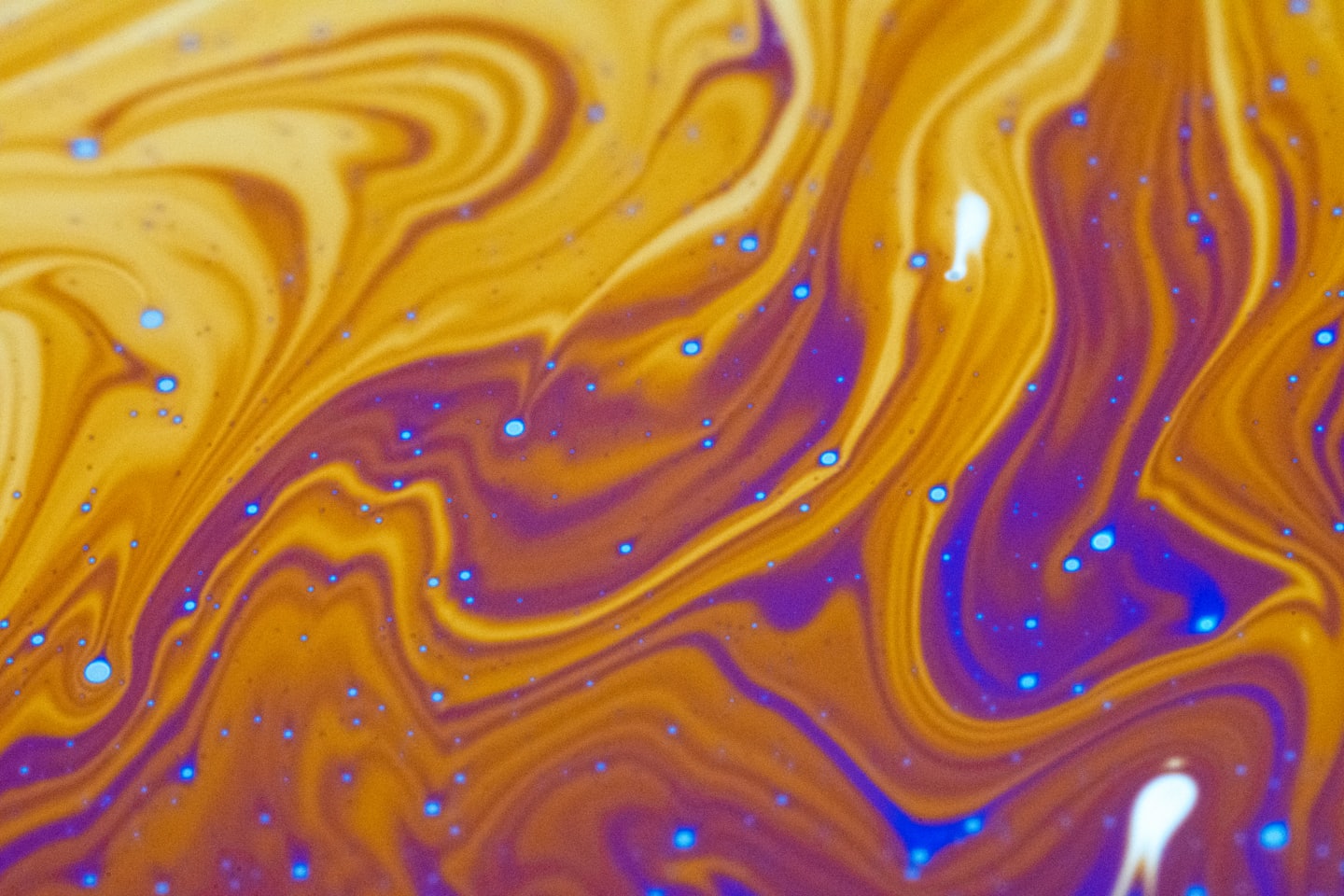 Swirling iridescent patterns move across a liquid surface.